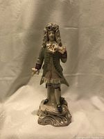Full view of the porcelain figurine showing the entire figure of the man in period costume on an ornate base.
