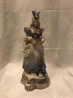 Full view of the porcelain figurine showing the entire figure and base with detailed dress and hat.