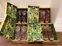 Four pairs of Fly London ladies sandals in branded boxes with a yellow and green cityscape design.