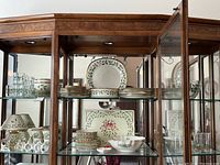 Display of multiple Lenox Holly Berry plates, bowls, mugs and glasses in a glass-front cabinet