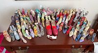 Top-down overview of about 40 miniature collector shoes in various colors and designs on a wooden surface.