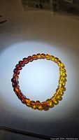 Photo showing the amber bracelet with a visible gradient from dark reddish to yellow amber under direct light