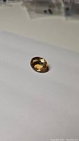 Oval cut golden citrine gemstone on white background, showing facets and color.