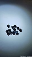 Twelve natural black onyx round cabochon gemstones scattered on a white surface, showing size and shape.