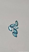 Six natural blue apatite marquis cut gemstones on a plain background, arranged loosely.