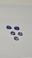 Five loose light blue sapphires, two pear/teardrop shape and three oval, displayed on a neutral background.