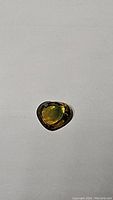 Heart-shaped deep golden yellow blue sapphire on white background, showing its size and shape