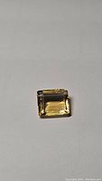 Top view of the rectangular emerald cut golden citrine gemstone showing clean facets and transparent light golden-yellow color.