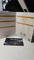 Photo showing GRA Moissanite grading report and anti-counterfeit warranty card.