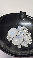 Overview of polished rainbow moonstone stones and beads in a black dish.