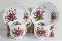 Front view of two Paragon Fine Bone China teacups and two matching saucers with Flower Festival floral pattern and gold trim.