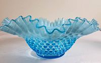 Side view of blue opalescent hobnail bowl showing ruffled edge and textured body.