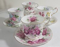 Front view of the four Paragon bone china teacups and saucers, showing varied floral patterns and gold rim details.