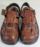 Top view of brown leather men's sandals with woven design and adjustable buckles.