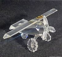 Close-up image of the clear faceted Bohemia crystal airplane figurine showing the propeller, wings, and wheels with sticker on wing.