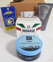 Photo showing four grooming products: Proraso shaving soap in a bowl, d:fi D:Struct hair cream with blue lid, Sean Jean I AM KING shower gel, and Blackberry Honey lip balm in yellow packaging.