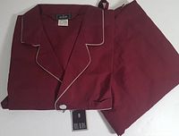 Photo of folded deep burgundy men's pajama set with white piping, including shirt and pants with tags.