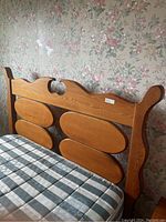 Close-up photo of wooden decorative headboard with four large oval panels and detailed carvings.