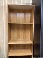 Front view of wooden book shelf showing three shelves and wood grain finish.