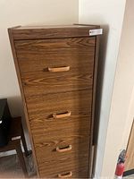 Front view of the wooden filing cabinet showing 4 drawers and wooden handles.