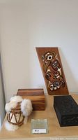 Lot displayed on table showing wooden jewelry boxes/chests, wooden plaque with First Nations artwork, handmade animal skin mini drum with fur trim, and Inukshuk stone coaster.