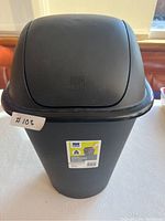 Front view of 30L black plastic garbage bin with swing lid and label attached