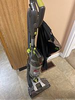 Front and side view of upright Hoover vacuum cleaner showing main unit, handle, and attached bag.