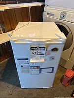 White Igloo mini fridge with energy consumption label and stickers on front, showing front view and top lid closed.