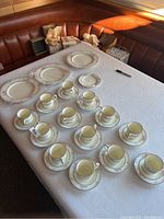 Top view of the set arranged on a table showing large plates, the small plate, with 13 teacups and 13 saucers neatly placed.