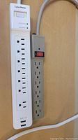 Photo showing white CyberPower power bar with six outlets, reset/protected switch, and gray power bar with six outlets and red switch