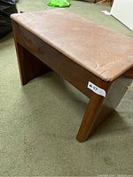 Front angled view showing the leather seat and wooden legs of the sewing stool.