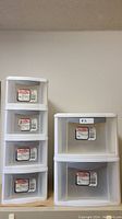 Four white Sterilite plastic drawer units with four drawers each.