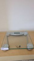 Full view of the Taylor glass digital bathroom scale showing transparent glass platform and silver digital display section.