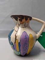 Side view showing hand painted floral design with purple, yellow, and blue colors plus brown painted rim and angled handle.