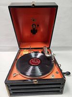 Open antique Victrola talking machine with vinyl record on turntable, visible tonearm and needle.