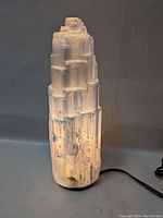 Front view of the white crystal lamp illuminated, showing natural ridged crystal structure and light diffusion.