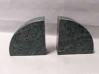 Pair of green marble book ends shown side by side on white surface with front-facing curved sides visible.