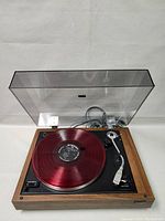 Front view with red vinyl record on platter and dust cover open