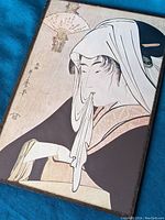 Close-up of the vintage Japanese woodblock print showing a woman in traditional attire holding a cloth to her mouth.