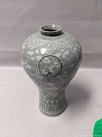 Front view of a Korean celadon vase showcasing circular crane motifs, floral designs, and a narrow, slightly flared opening at the top.