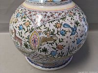 Side close-up showing intricate hand painted floral and animal designs on the curved base of the vase.