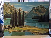 Full view of the landscape painting showing the lake, mountains, and trees under natural light.