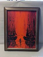 Full view of the framed painting showing two ships silhouetted against a red background.