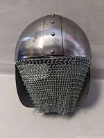 Front view of steel helmet with chain mail hanging from the bottom edge.