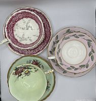 Top view showing all three vintage teacups with saucers, each with unique floral patterns and gold trims.