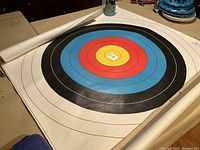 Photo showing one giant archery target rolled partially unrolled on a table, vibrant FITA rings with no damage.