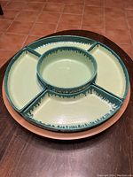 Top view of wooden Lazy Susan tray with green-glazed pottery serving dishes fitted in place
