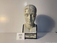 Front view of the white ceramic phrenology head showing labeled sections on forehead and scalp, and text on base.
