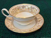 Single tea cup and saucer showing gold Florentine pattern and handle detail