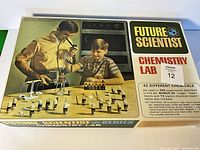 Box front showing brand name Future Scientist Chemistry Lab, depicting man and boy conducting chemistry experiments with various jars and equipment on table.